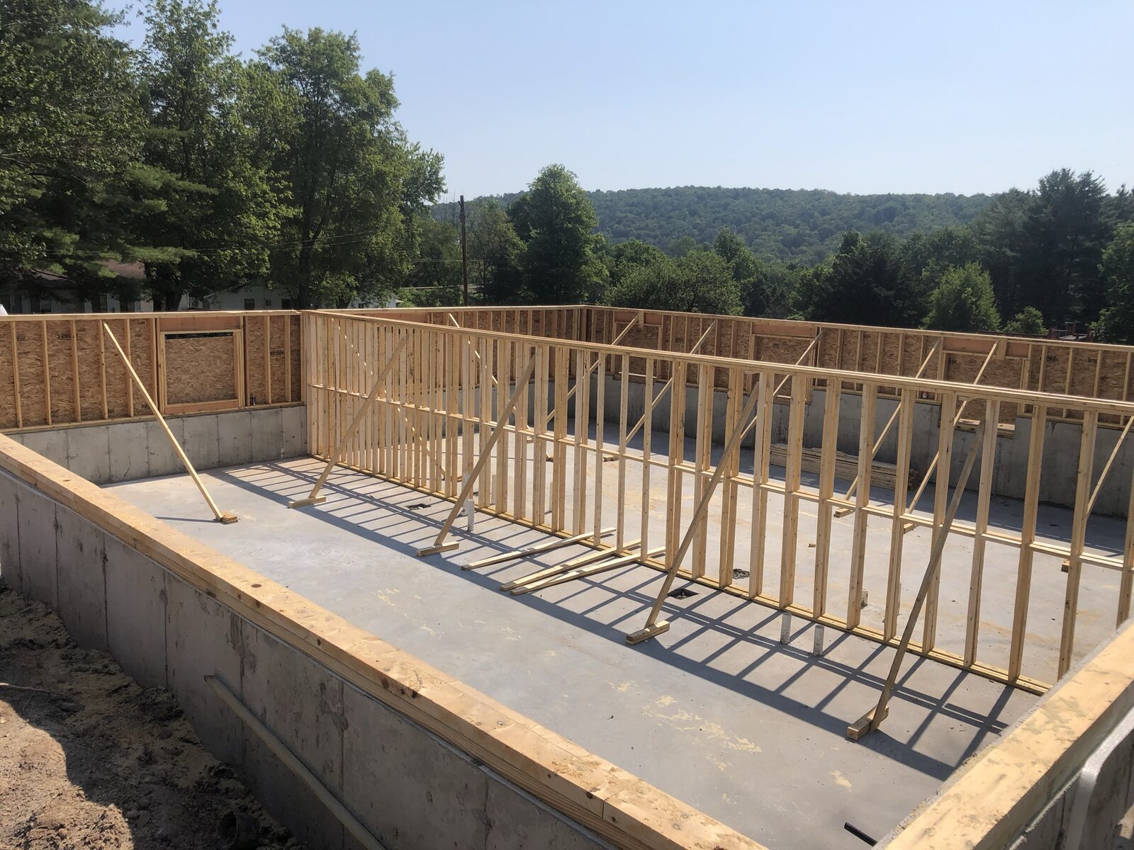Fresh concrete foundation with first-floor wall framing going up