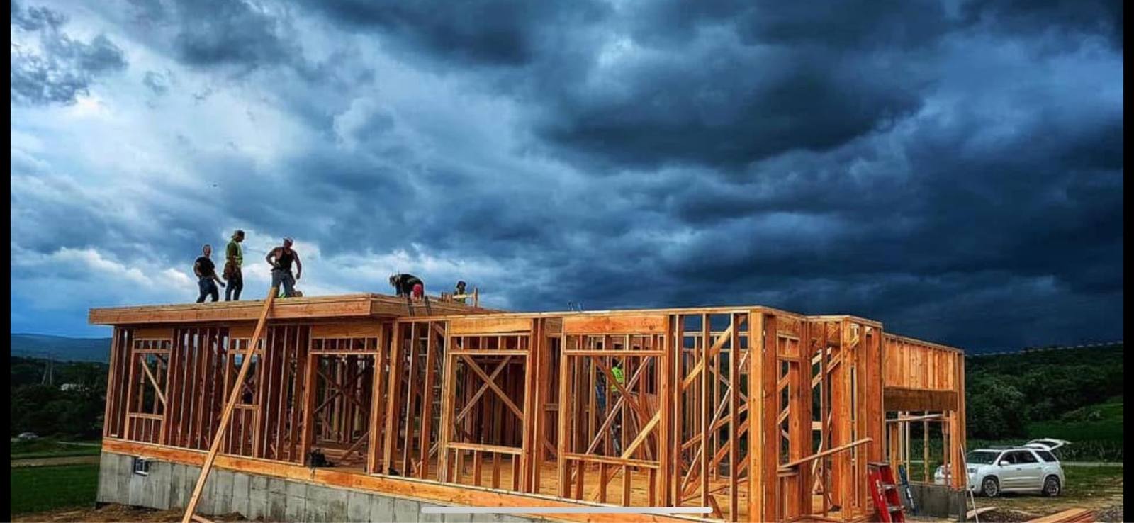 Crew framing roof trusses under a dramatic storm sky