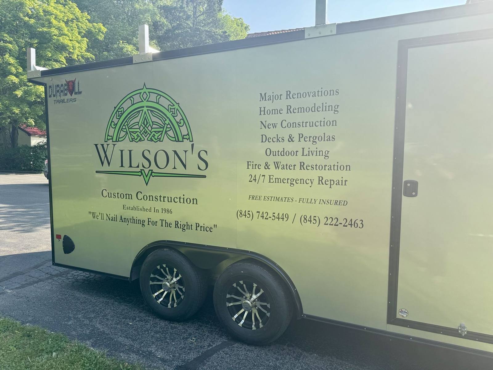 The Wilson's Custom Construction branded work trailer with logo and service list